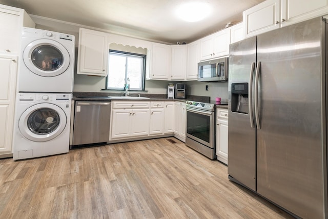 104 3rd Ave NW, Winchester, TN 37398 - kitchen featuring appliances with stainless steel finishes, a sink, stacked washer / dryer, light wood finished floors, and dark countertops