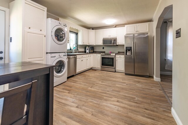 104 3rd Ave NW, Winchester, TN 37398 - kitchen featuring appliances with stainless steel finishes, stacked washer / drying machine, dark countertops, light wood-style floors, and a sink