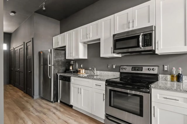 1700 Belcourt Ave Unit 103, Nashville, TN 37212 - kitchen featuring stainless steel appliances, light wood-type flooring, white cabinetry, light stone countertops, and a sink