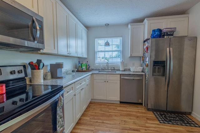 2659 Cave Springs Rd, Springfield, TN 37172 - kitchen featuring appliances with stainless steel finishes, a sink, white cabinets, light wood-type flooring, and light stone countertops