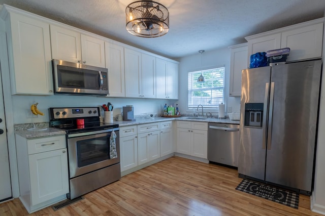 2659 Cave Springs Rd, Springfield, TN 37172 - kitchen featuring stainless steel appliances, white cabinetry, light wood-style floors, a sink, and a textured ceiling