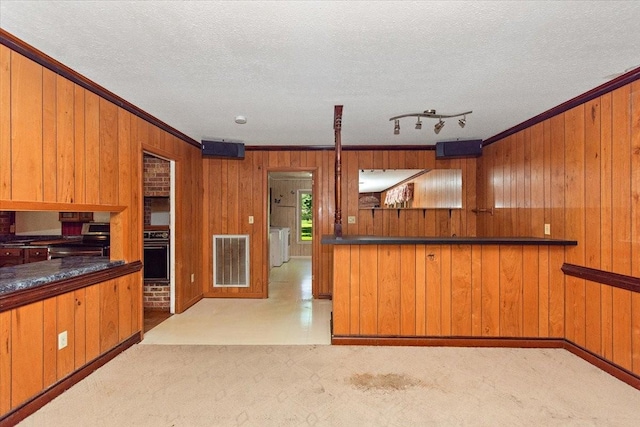 103 Colwell Ln, Manchester, TN 37355 - kitchen with stainless steel electric range oven, ornamental molding, wood walls, brown cabinetry, and oven