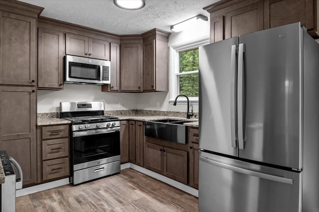 1079 Hillcrest Rd, Waverly, TN 37185 - kitchen with appliances with stainless steel finishes, light wood finished floors, a sink, light stone counters, and a textured ceiling