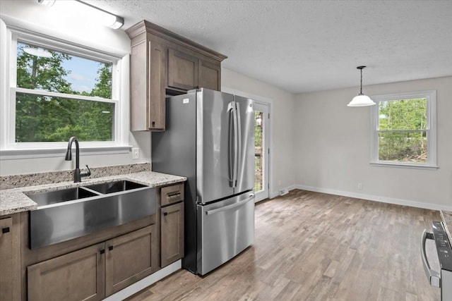 1079 Hillcrest Rd, Waverly, TN 37185 - kitchen with freestanding refrigerator, a sink, light wood-type flooring, light stone counters, and decorative light fixtures