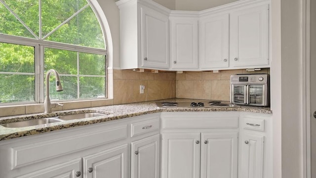 517 Eversholt Ct, Antioch, TN 37013 - kitchen featuring a sink, white cabinets, tasteful backsplash, and light stone countertops