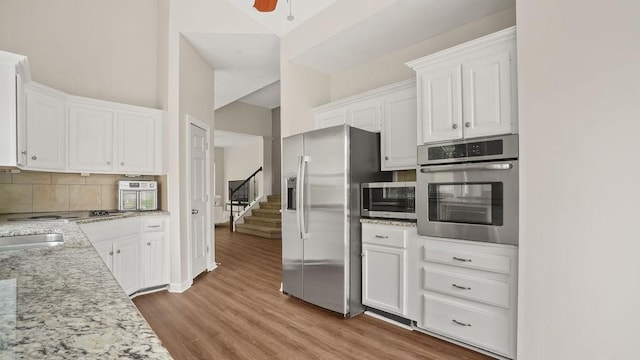 517 Eversholt Ct, Antioch, TN 37013 - kitchen with stainless steel appliances, white cabinets, tasteful backsplash, light wood-style flooring, and light stone counters