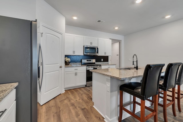 5312 Owens Ln, White House, TN 37188 - kitchen featuring stainless steel appliances, a sink, a kitchen breakfast bar, light wood finished floors, and white cabinets