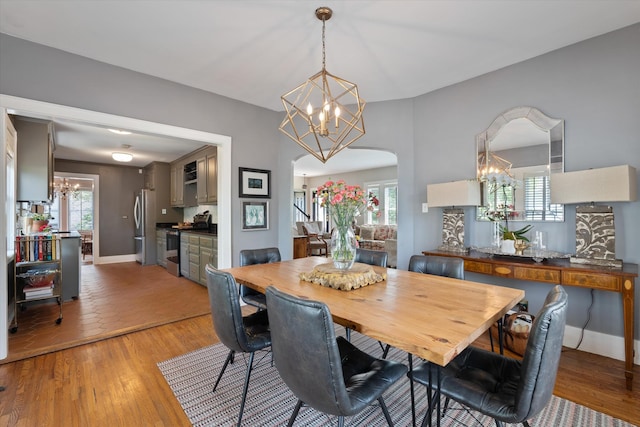 2209 Natchez Trce, Nashville, TN 37212 - dining room featuring a chandelier, light wood-style flooring, arched walkways, and baseboards