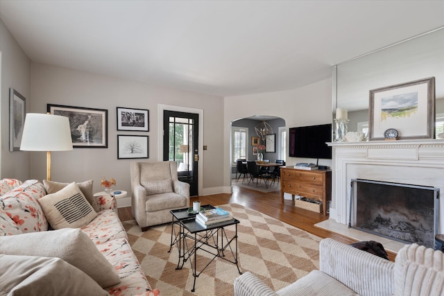 2209 Natchez Trce, Nashville, TN 37212 - living room featuring arched walkways, light wood-style floors, baseboards, and a fireplace with raised hearth