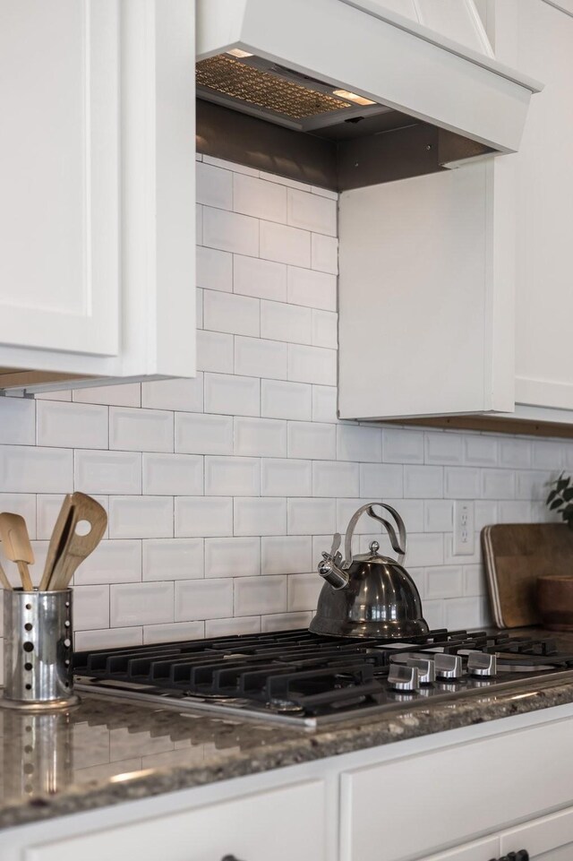 2060 Bushnell Farm Dr, Franklin, TN 37064 - kitchen featuring white cabinets, tasteful backsplash, dark stone countertops, custom range hood, and stainless steel gas stovetop
