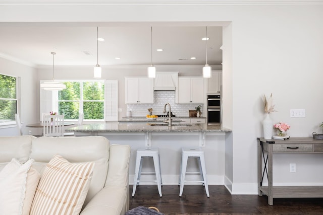 2060 Bushnell Farm Dr, Franklin, TN 37064 - kitchen with stainless steel double oven, white cabinetry, a breakfast bar area, decorative backsplash, and a sink