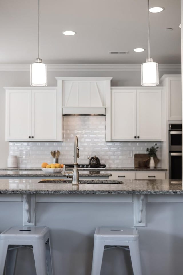 2060 Bushnell Farm Dr, Franklin, TN 37064 - kitchen with custom exhaust hood, multiple ovens, dark stone countertops, a breakfast bar, and crown molding