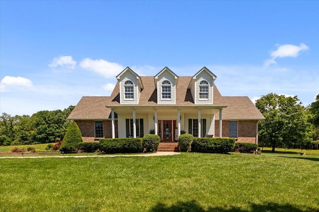 495 Baker Rd, Dickson, TN 37055 - cape cod house featuring covered porch, brick siding, a front lawn, and roof with shingles
