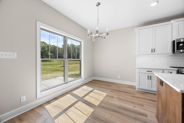 1456 Sango Commons Way, Clarksville, TN 37043 - kitchen with stainless steel microwave, a chandelier, light countertops, white cabinetry, and baseboards