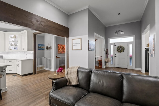 entrance foyer featuring light wood-style floors, ornamental molding, a chandelier, and baseboards