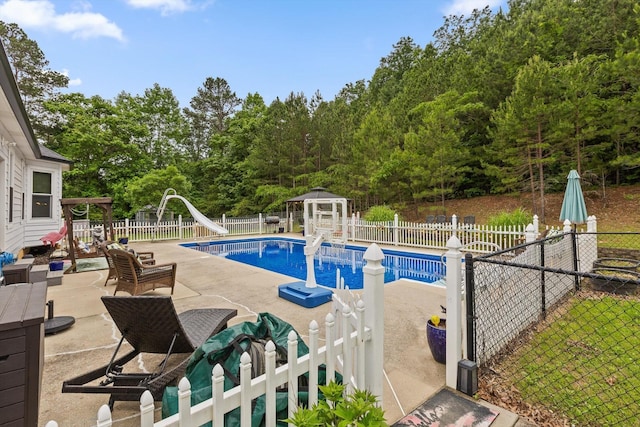 view of pool featuring a water slide, a gazebo, a patio area, and a fenced backyard