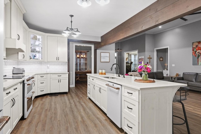 kitchen featuring range with two ovens, a chandelier, a sink, dishwasher, and open floor plan