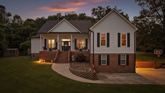 view of front of property featuring stairs, covered porch, a front lawn, and brick siding