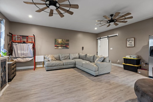 living room with a ceiling fan, a barn door, light wood-type flooring, and recessed lighting
