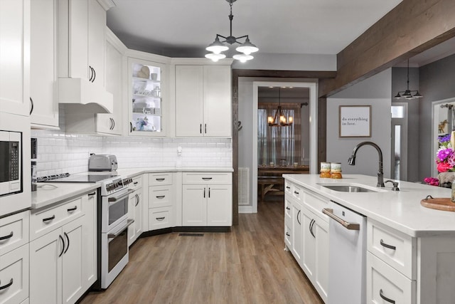 kitchen featuring a chandelier, white appliances, a sink, under cabinet range hood, and light countertops