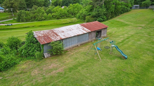 view of green lawn with an outbuilding, an outdoor structure, and a playground