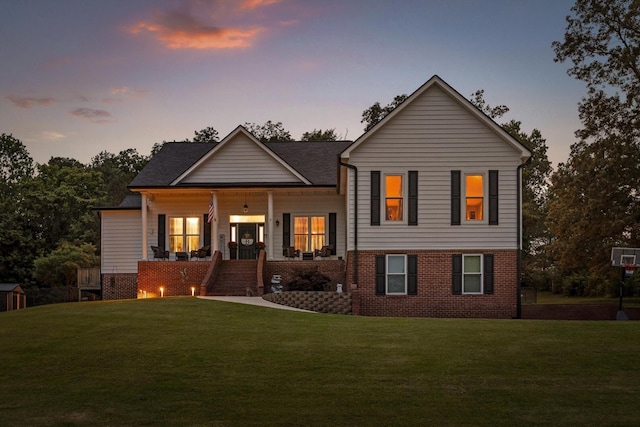 view of front facade featuring a lawn, a porch, brick siding, and stairs