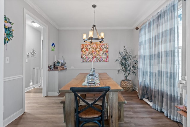 dining area featuring a chandelier, wood finished floors, baseboards, and ornamental molding