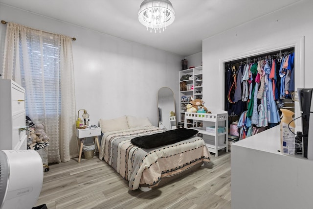 bedroom featuring light wood-style flooring, a chandelier, and a closet