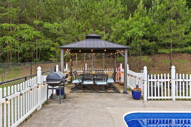 view of patio featuring a gazebo, a forest view, and outdoor dining area
