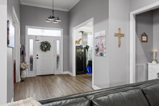 entrance foyer with wood finished floors, crown molding, and baseboards