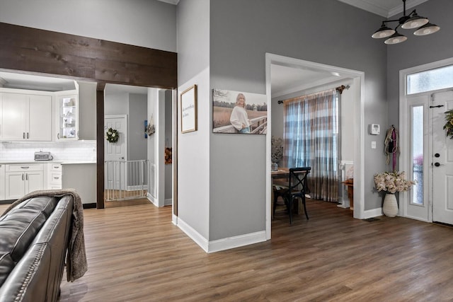 entryway with light wood finished floors, baseboards, and ornamental molding