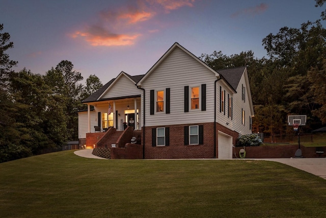 view of front of property with driveway, a lawn, a garage, brick siding, and stairs