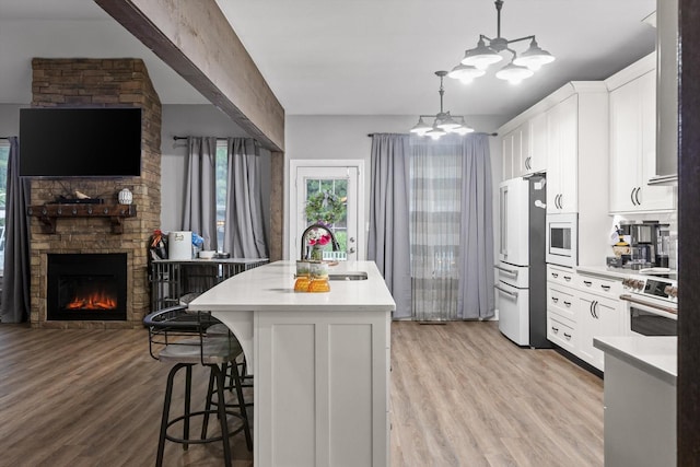kitchen with white appliances, a sink, a breakfast bar, a chandelier, and a kitchen island