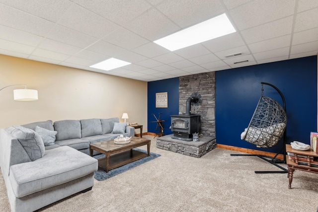 4455 Tarsus Rd, Palmyra, TN 37142 - living room featuring a wood stove, carpet flooring, a drop ceiling, and baseboards