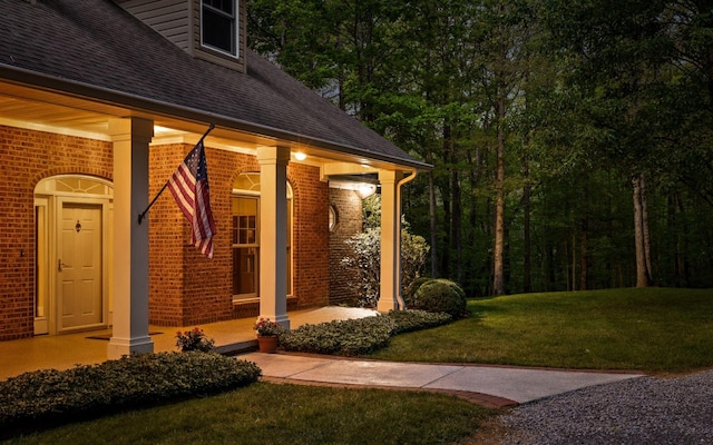 2385 Clear Brooks Dr, Signal Mountain, TN 37377 - view of exterior entry with a shingled roof, brick siding, covered porch, and a yard