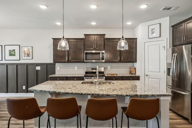 321 Union Pier Dr, Mount Juliet, TN 37122 - kitchen with stainless steel appliances, a sink, dark brown cabinetry, a breakfast bar area, and a kitchen island with sink