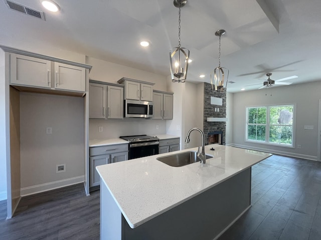 54 Charleston Cv, Clarksville, TN 37043 - kitchen featuring appliances with stainless steel finishes, gray cabinetry, dark wood-style flooring, open floor plan, and a fireplace