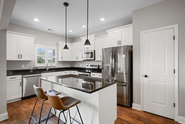 102 Murrell Rd, Dickson, TN 37055 - kitchen featuring appliances with stainless steel finishes, dark wood-type flooring, white cabinets, a breakfast bar, and a center island
