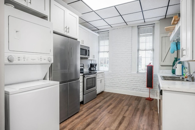 105 W Walnut St, Smithville, TN 37166 - kitchen featuring appliances with stainless steel finishes, a sink, stacked washer / drying machine, brick wall, and white cabinets