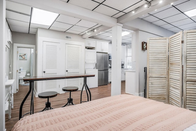 105 W Walnut St, Smithville, TN 37166 - kitchen featuring estacked washer and dryer, freestanding refrigerator, light wood-style flooring, a paneled ceiling, and white cabinetry