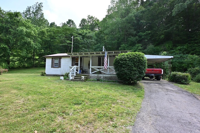 9097 Denton Rd, Linden, TN 37096 - manufactured / mobile home with a porch, asphalt driveway, a front yard, a wooded view, and a carport