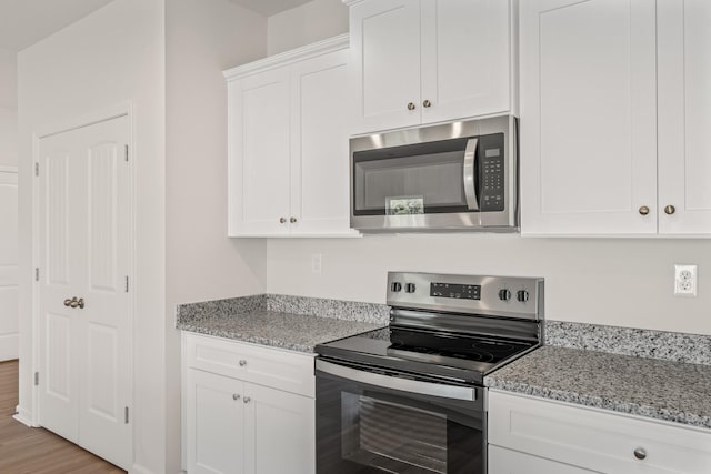 2042 Lala Loop, White Bluff, TN 37187 - kitchen featuring appliances with stainless steel finishes, white cabinets, light stone countertops, and light wood-style floors