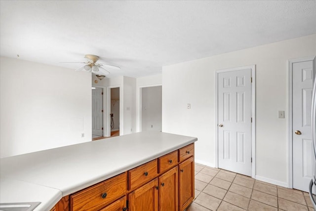 1910 Burlington Cir, Columbia, TN 38401 - kitchen with ceiling fan, brown cabinetry, light tile patterned floors, light countertops, and baseboards