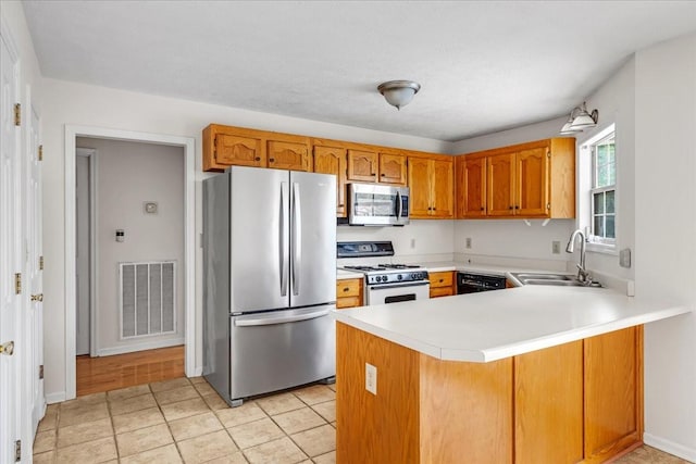 1910 Burlington Cir, Columbia, TN 38401 - kitchen featuring appliances with stainless steel finishes, a sink, a peninsula, and brown cabinetry