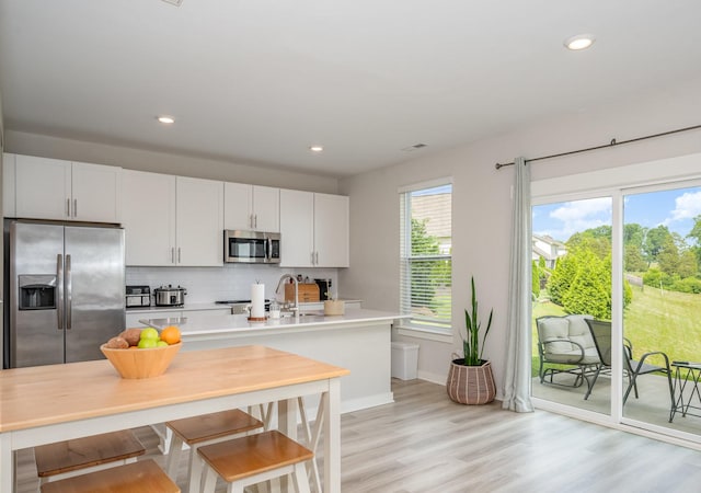 705 Watson Ct, Spring Hill, TN 37174 - kitchen featuring stainless steel appliances, a sink, light wood-style floors, backsplash, and light countertops