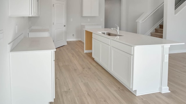 1247 Linn Cove Ct, Gallatin, TN 37066 - kitchen with a sink, light wood finished floors, a kitchen island with sink, baseboards, and white cabinetry