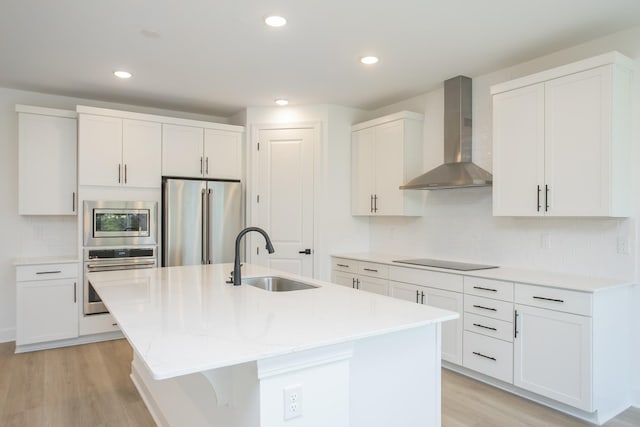 122 W Cassa Way, Mount Juliet, TN 37122 - kitchen featuring appliances with stainless steel finishes, wall chimney range hood, a sink, light wood-style flooring, and a center island with sink