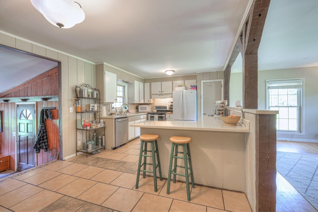 1111 Greenhill St, Murfreesboro, TN 37129 - kitchen featuring stainless steel appliances, a peninsula, light countertops, a breakfast bar, and white cabinetry