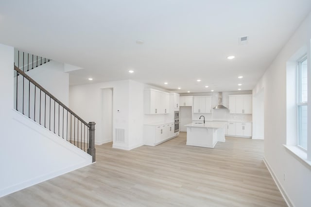 133 W Cassa Way, Mount Juliet, TN 37122 - kitchen featuring wall chimney range hood, light wood-type flooring, a center island with sink, white cabinets, and recessed lighting