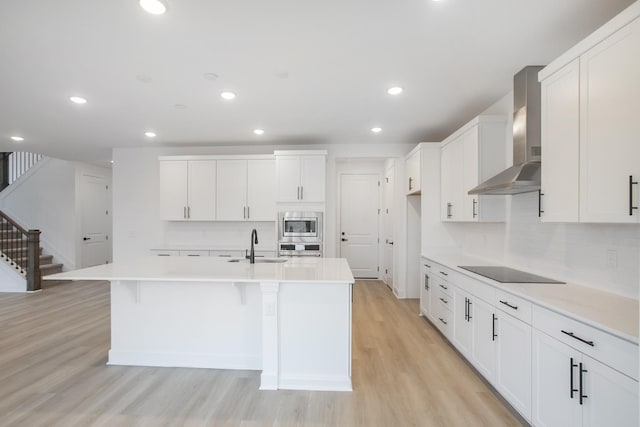 133 W Cassa Way, Mount Juliet, TN 37122 - kitchen with wall chimney range hood, appliances with stainless steel finishes, an island with sink, tasteful backsplash, and light wood-style flooring